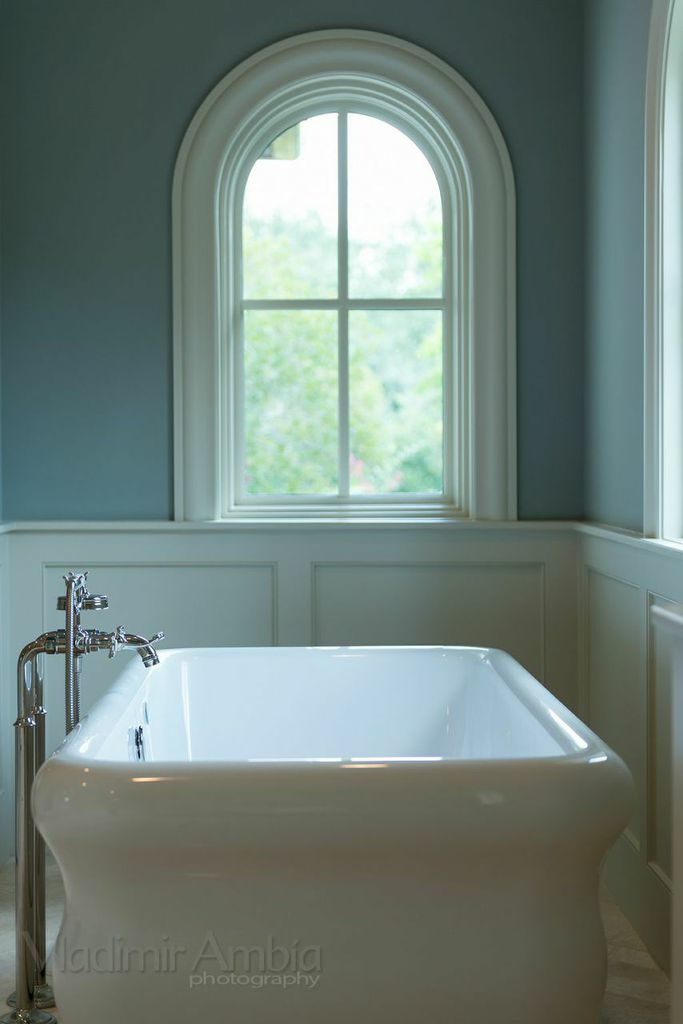custom Mediterranean Revival style home bathroom with tub and rounded window